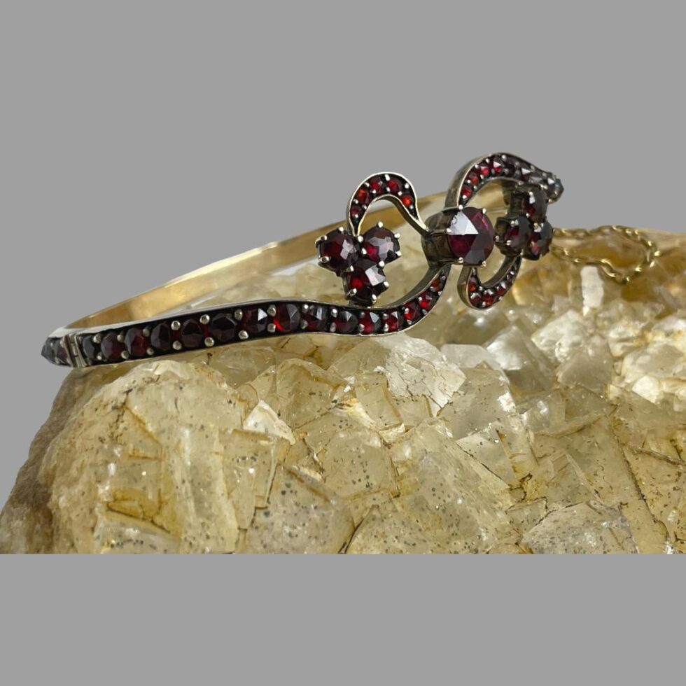 Photo of antique garnet bracelet displayed on rock of natural river quartz with the bracelet front facing to the right.