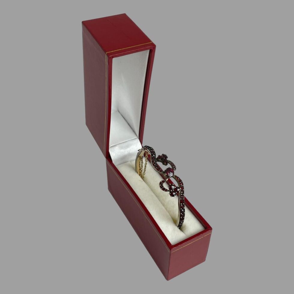 Photo of the antique garnet bracelet displayed inside its modern red covered bracelet box with off white interior.
