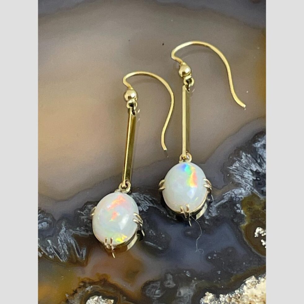 Photos of earrings displayed flat on a slice of natural agate with the opals facing up.