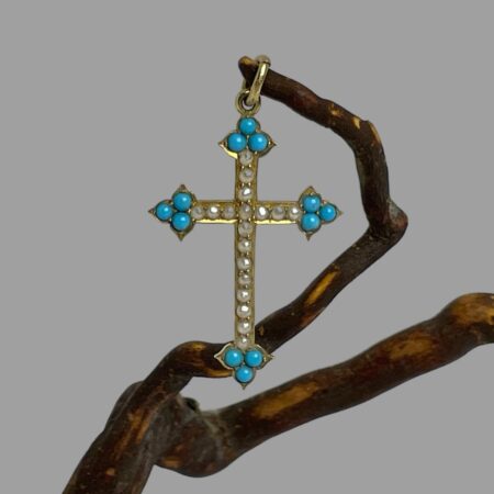 Main photo of antique 18Kt gold cross displayed hanging from a twig from a cherry tree by its bail. This petite antique cross has arrow head tips set with 3 sleeping beauty turquoise stones and seed pearls lining the rest of the cross. A fine gold chain would be ideal for this cross.