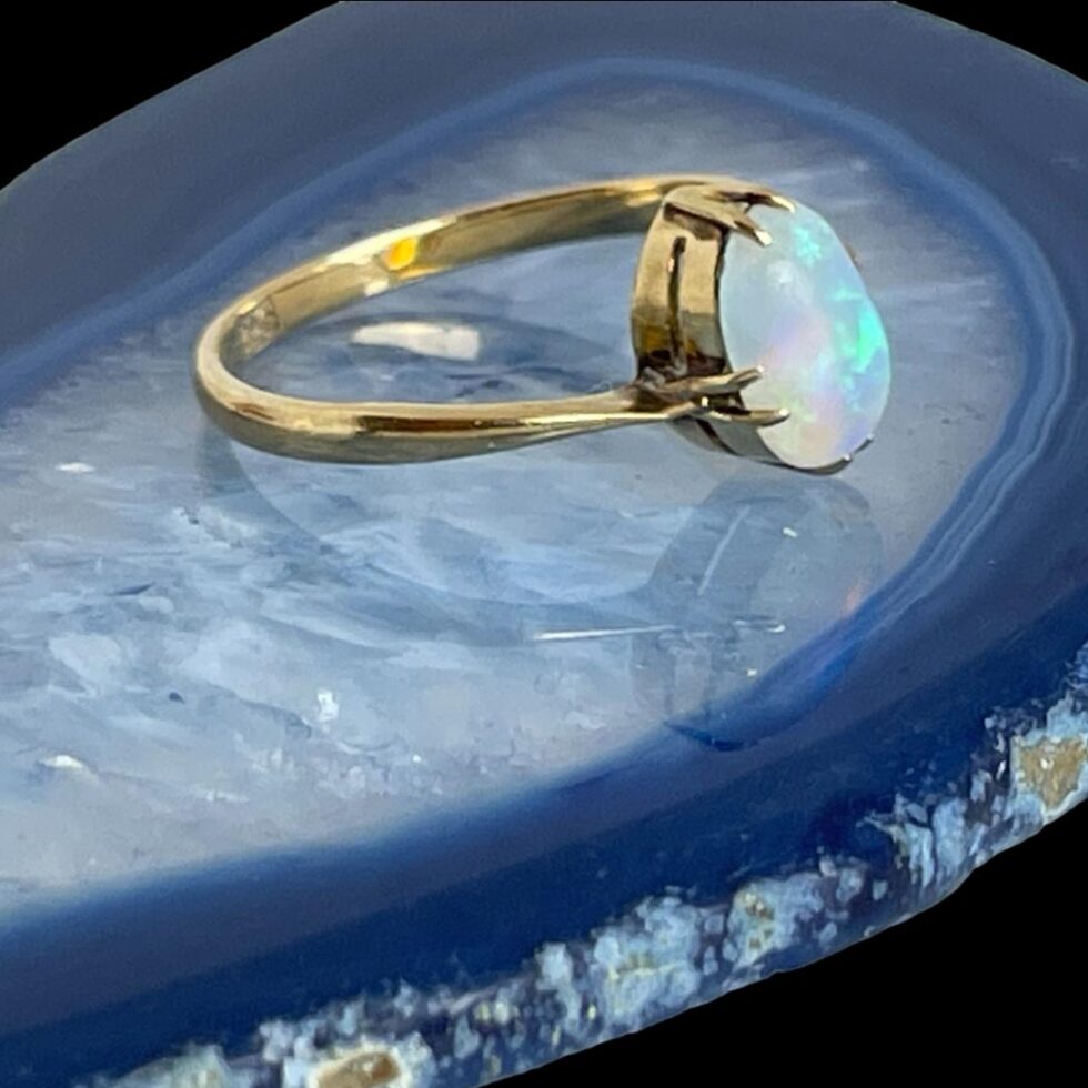 Photo of ring in close up still displayed on a slice of blue agate this time with the ring front facing right.