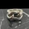 Main photo of Pomellato gourmet knot ring displayed on top of a block of black marble and the ring front forward facing. The ring appears like a rope knot but is in fact 2 pieces of tubular silver. One piece makes up the band and shoulders - imagine a rubber band that has been set in silver and moulded into a solid form. The front of the ring is a separate smaller tubular band that has been weaved within the main band to create a knot look.