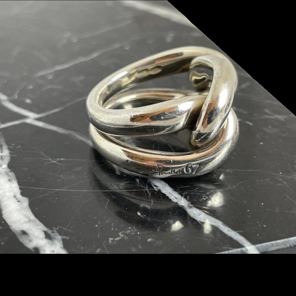 Photo of Pomellato knot ring displayed on black marble with the ring front facing right. The Pomellato 67 signature is visible on the lower band.