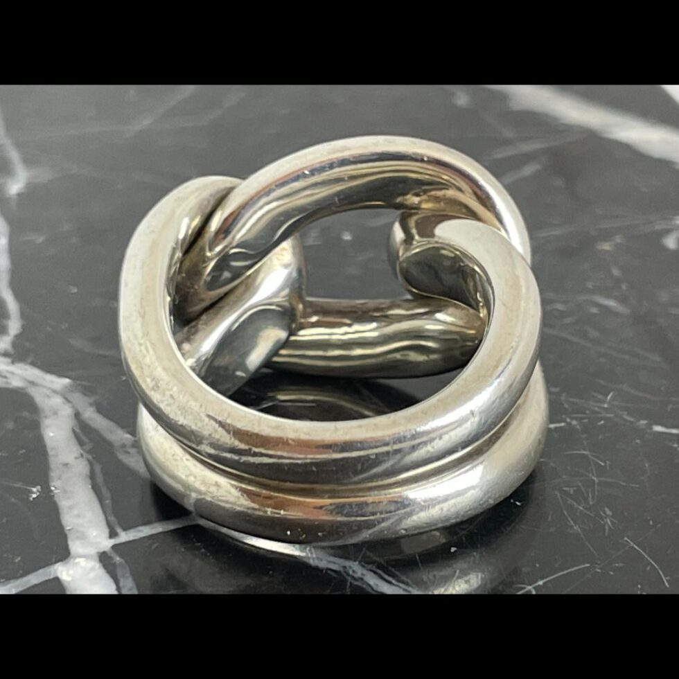 Photo of ring still on black marble with the ring front facing away from camera displaying the back of band.