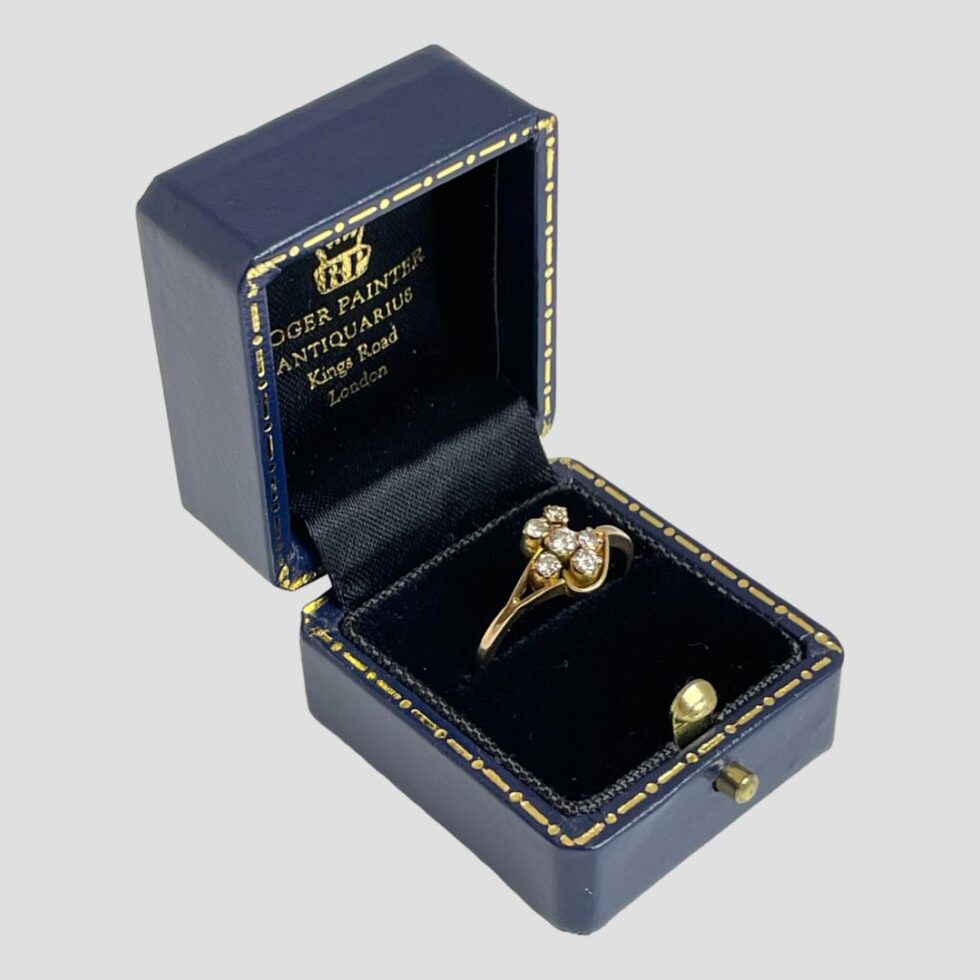 Another photo of gold diamond flower ring displayed in its box this time seen from a side angle with front of box open facing bottom right corner.