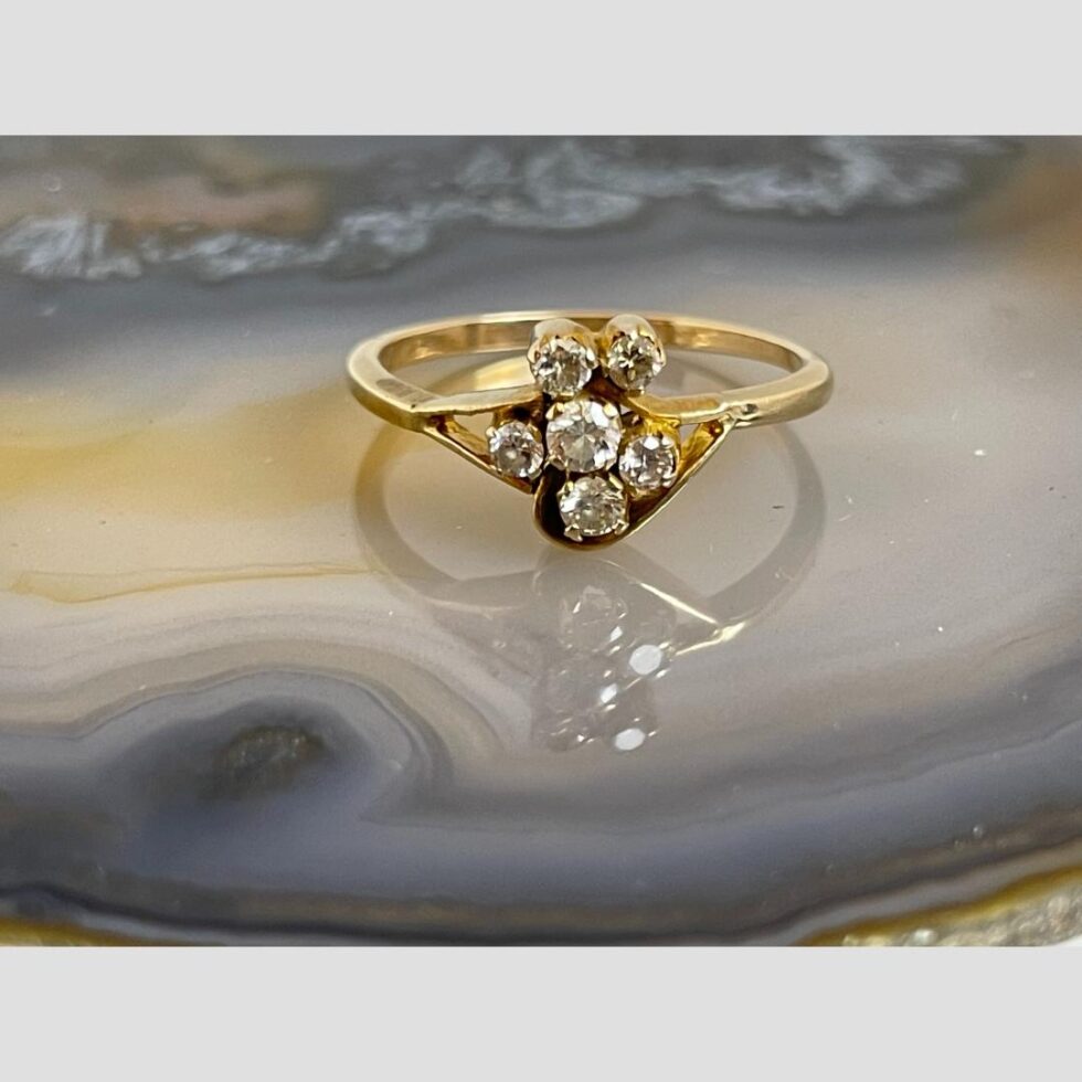 Photo of gold diamond flower ring displayed on a slice of natural agate with the ring front forward facing.