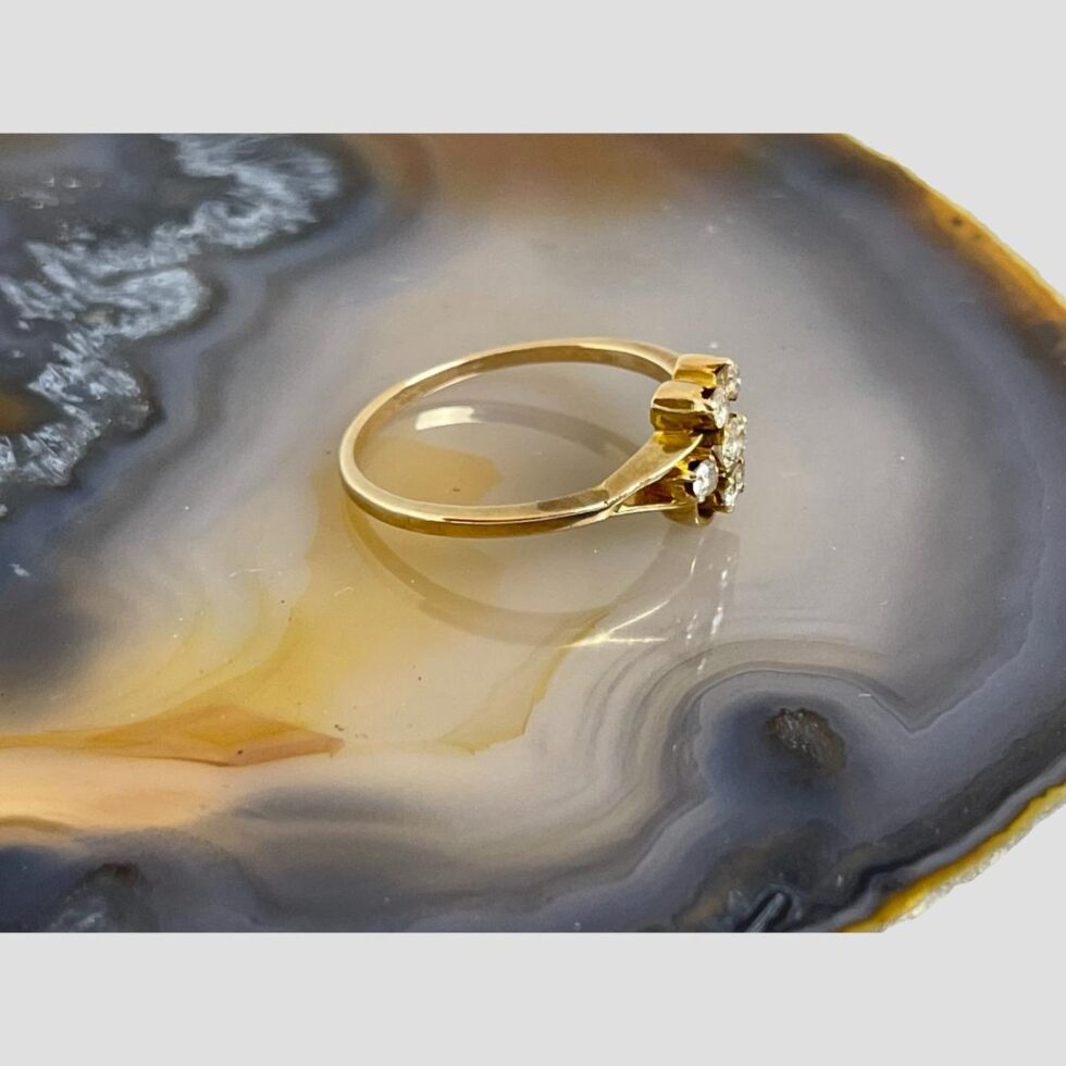 Photo of diamond flower ring displayed on a slice of natural agate with the ring front facing towards the right.