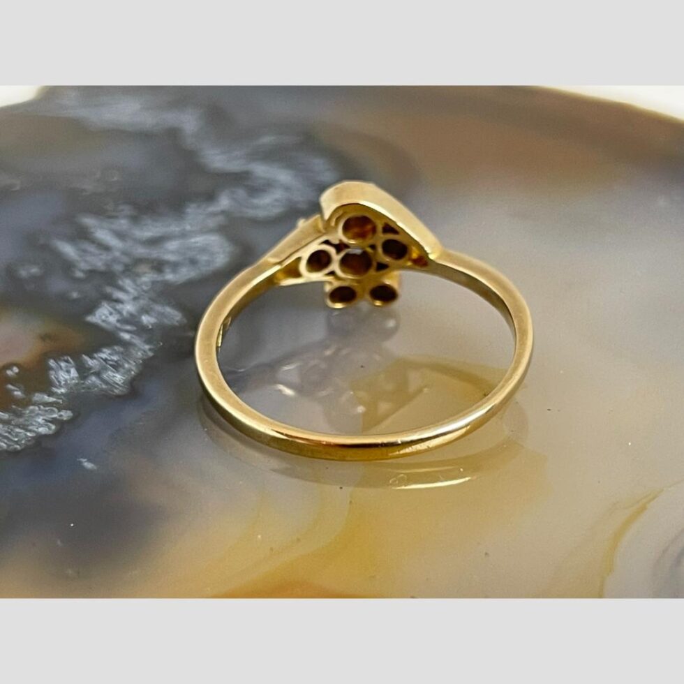 Photo of gold diamond flower ring facing away from the camera and showing the individual setting for each diamond.