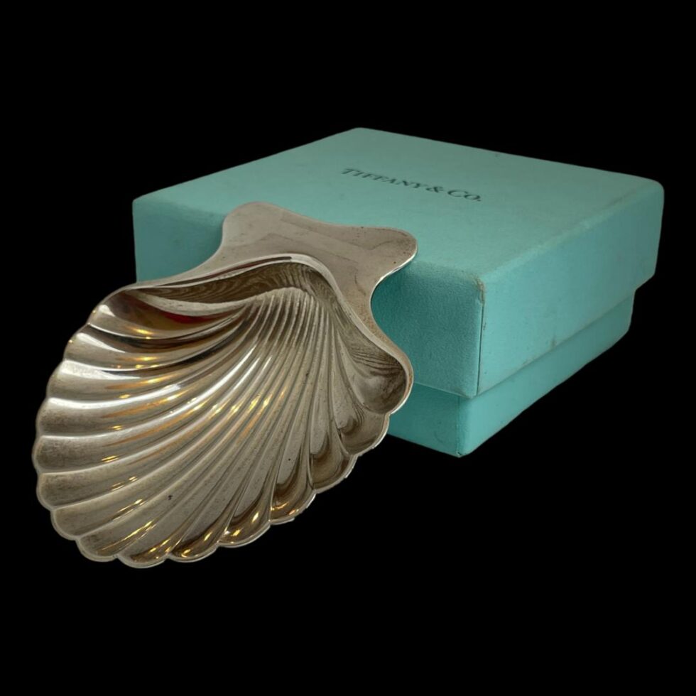 Photo of Tiffany shell shaped dish still with back edge leaning against the box but seen this time from a slight side angle with the front tip of the bowl pointing to the bottom left corner of the photo.