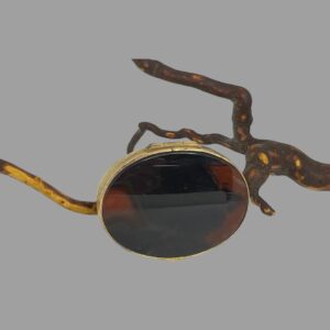 Main photo of antique agate pill/snuff box shown upright on one side and leaning against a twig. The side on display is the lid with the opening flap at the top. The agate on the lid is darker.