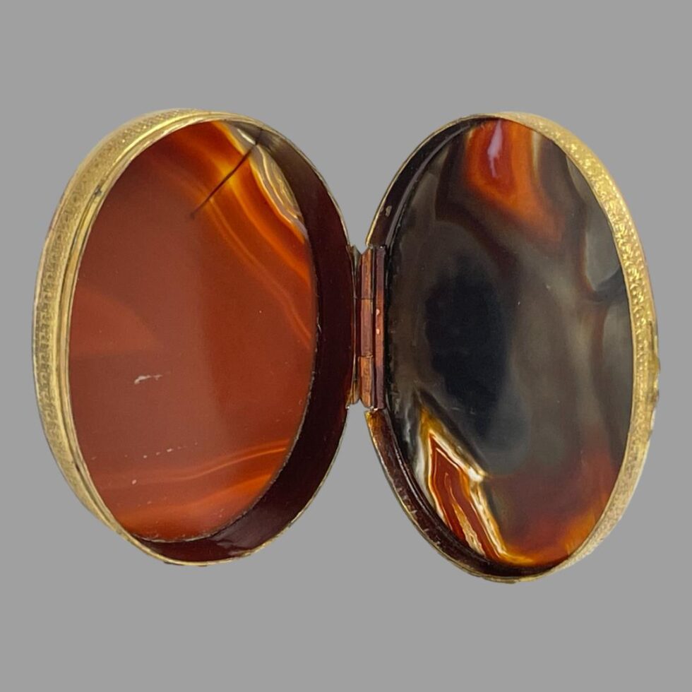 Photo of box shown open and leaning up like an open book. The colour of the 2 pieces of agate is highlighted in this photo with the light coming through.