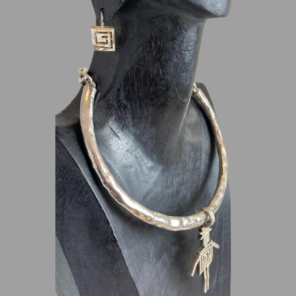 Photo of Biche de Bere set displayed on a dark wooden stand and seen from a side angle with the necklace front facing towards the right.