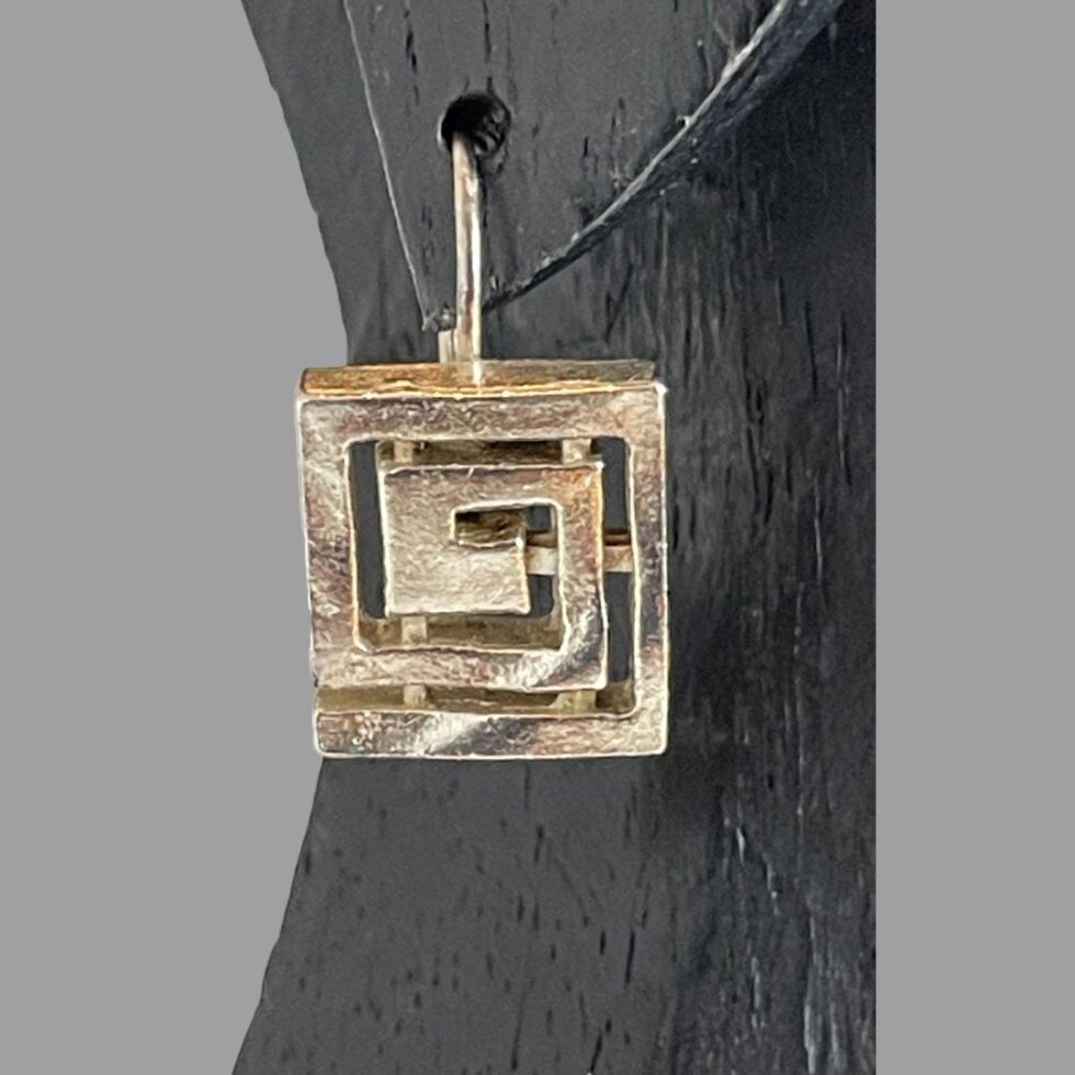 A close up photo of one of the earrings displayed in the ear of a display stand.