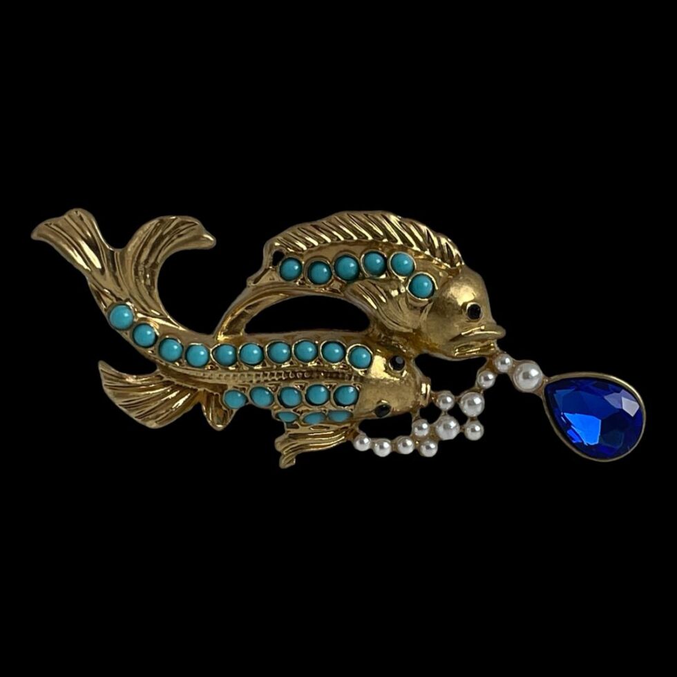 A photo of the brooch this time with the fish facing towards the right so the sideways view fish is at the top. The brooch is displayed against a black background which enhances the beauty of this wonderful brooch.