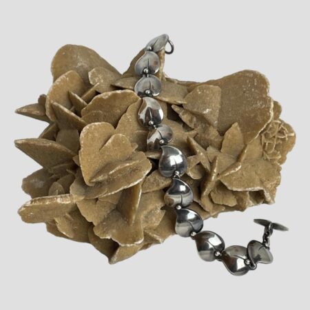 Main photo of N. E. From bracelet displayed across a rock of natural desert sand rose. The whale tail toggle end is in the foreground to the right.