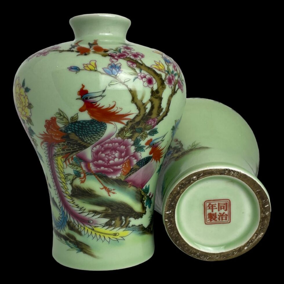 Photo of vases displayed with left hand one upright and showing an exotic bird and peony flower in close up and other laid flat with the red stamp to the base on display.