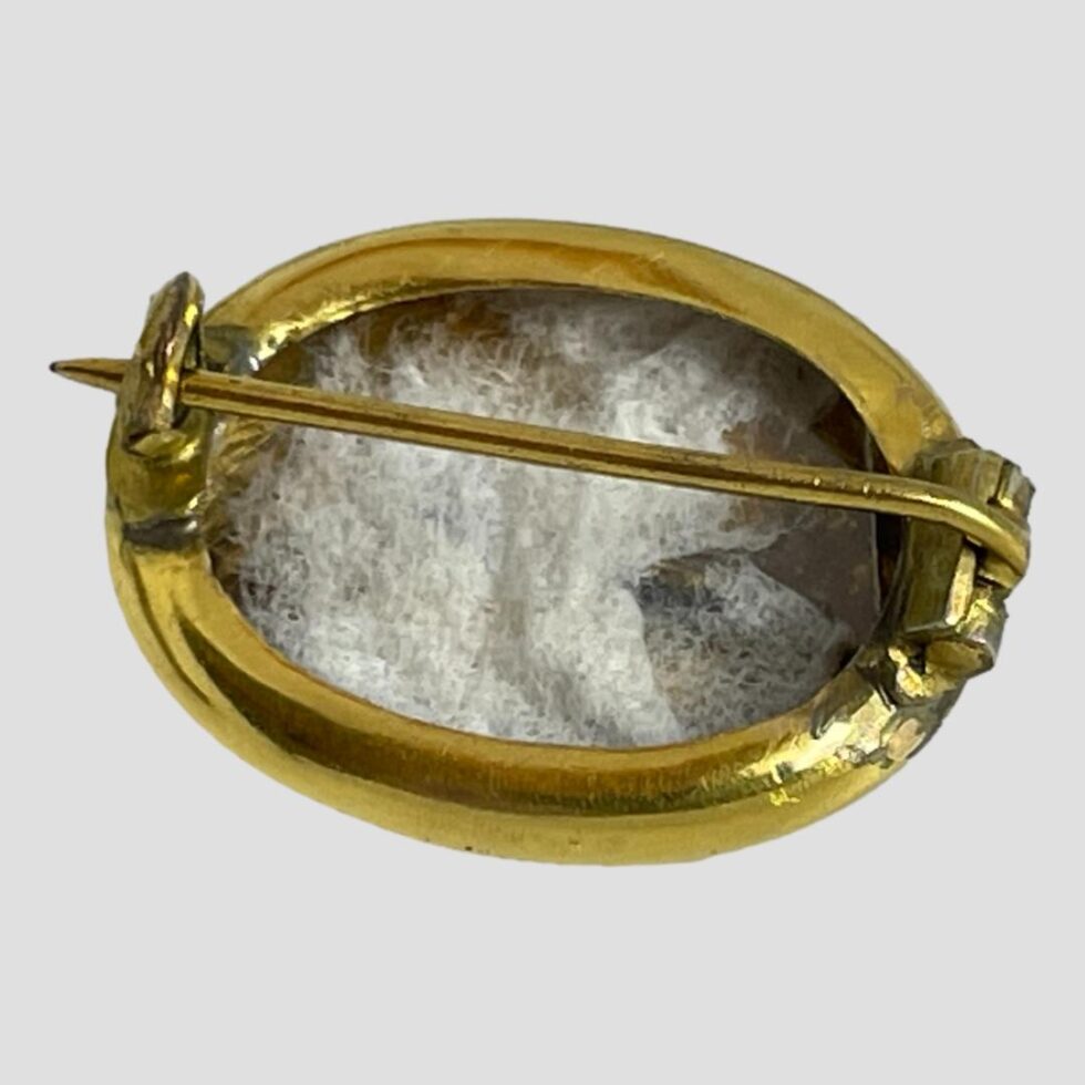 Photo of back of locket brooch shown with pin closed. There is some cotton padding inside the area where hair would originally been kept. There is quite some depth to the locket meaning it could hold not only hair but also a small picture or small keepsake. There is no cover though so something that won't fall out.