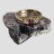Main photo of gold ruby diamond ring displayed on a rock of natural lepidolite. The ring front is forward facing with the pink ruby contrasting well with the milky purple hue of the lepidolite. The angle of the photo is slightly raised looking diagonally downward showing the front of ring and the inside of back band. The pink round cut ruby is a deep cerise colour and the small diamonds either side are set in white gold making the diamonds appear larger. The gallery is quite intricate in its detailing with the shoulders being very plain in contrast. A very sweet classic look ring.
