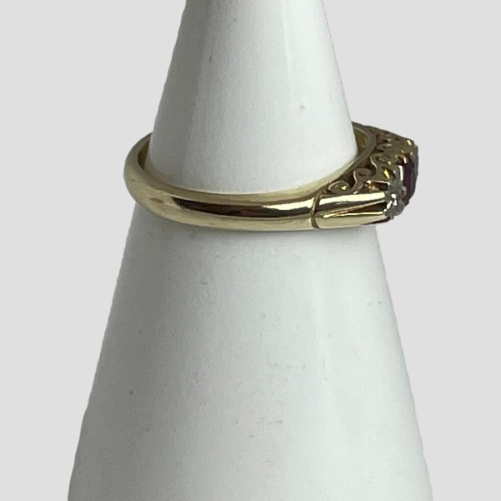 Photo of ring displayed on a cone shaped stand and seen with ring front facing right. From this angle, it is difficult to see the stones as the shoulders are high and plain. The intricate gallery area is visible.