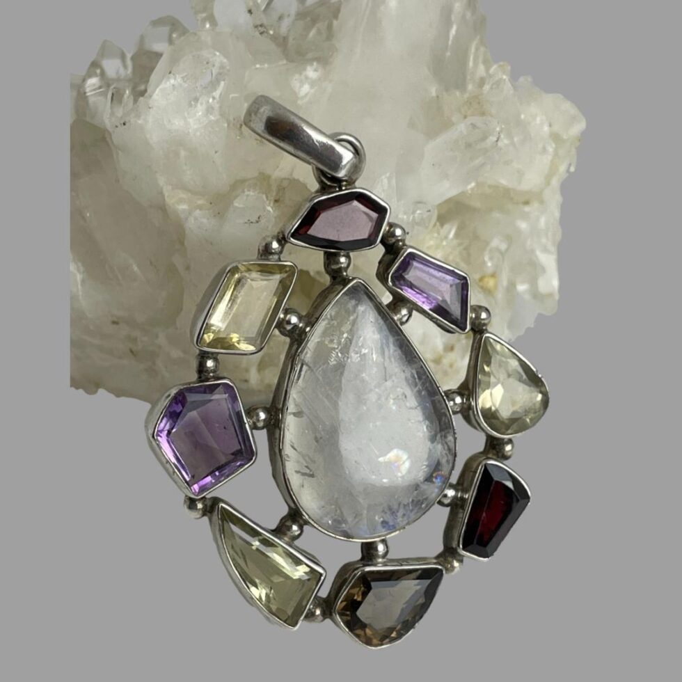 Photo of pendant this time leaning against the rock of quartz crysta. The moonstone is showing clear of blue colours in this image.