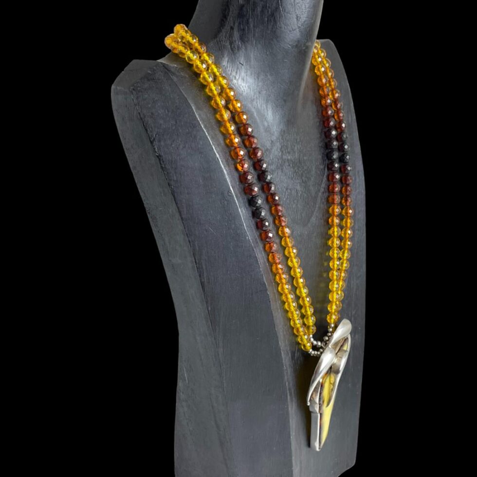 Photo of vintage multi amber necklace displayed on a dark wooden stand with the necklace front facing to the right.