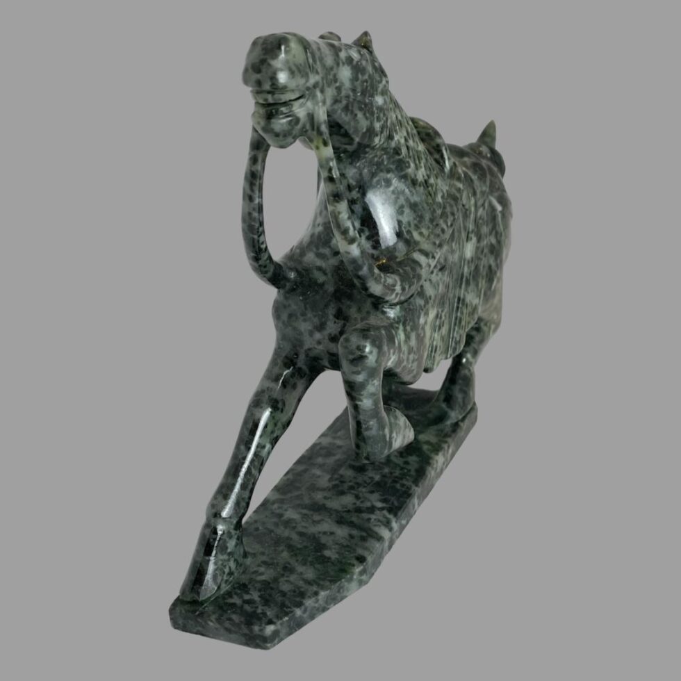 Photo of serpentine stone horse this time with the horse posed diagonally across the page so front end is facing left and hind is in top right. Incredible carving with even the reins carved from the stone.