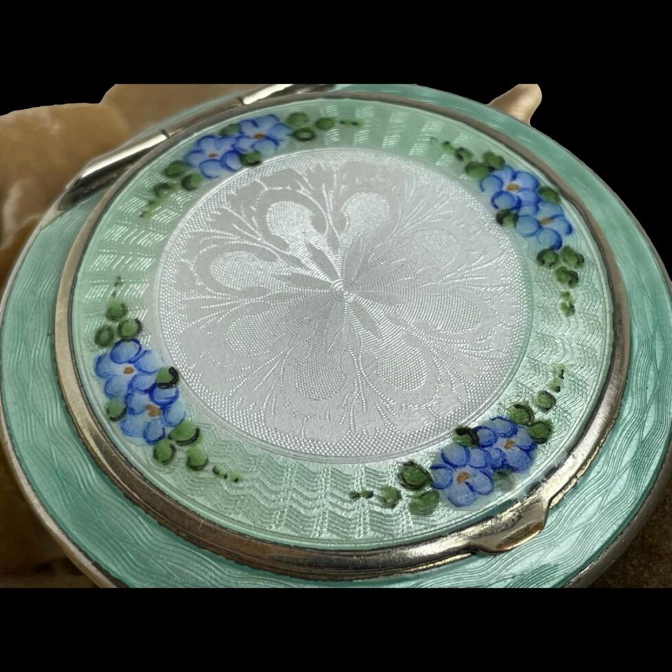 A close up photo of the enamel design detail to the top of compact.