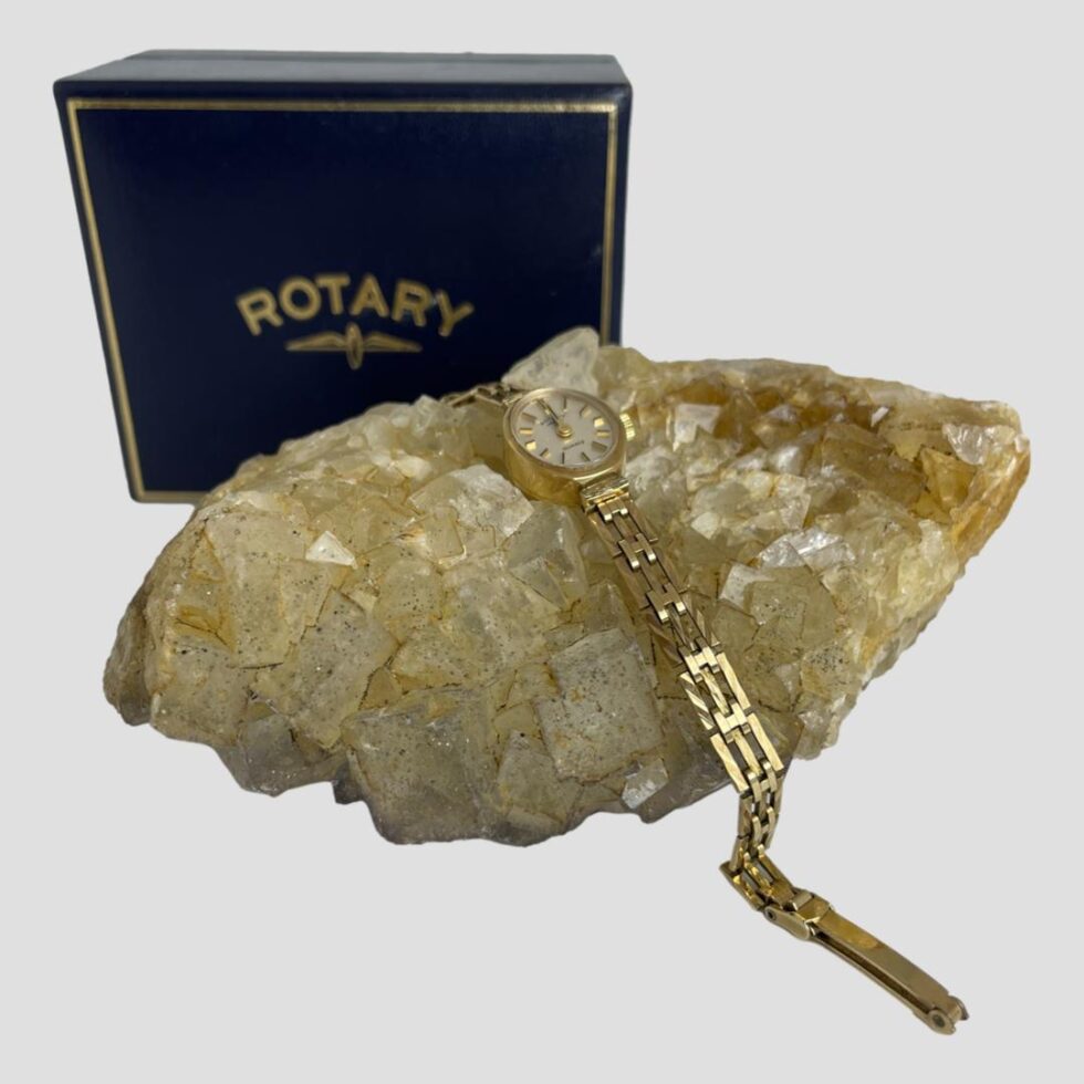 Photo of ladies Rotary watch displayed laid across a rock of natural river quartz. The original Rotary watch case is behind the rock to the left.