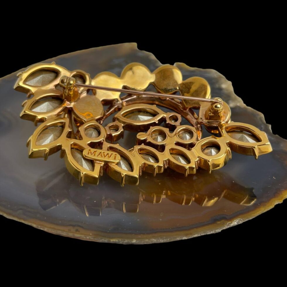 Photo of the back of Mawi London designer brooch seen from the back with pin closed. The MAWI mark is visible on a small oval plate attached at the back.