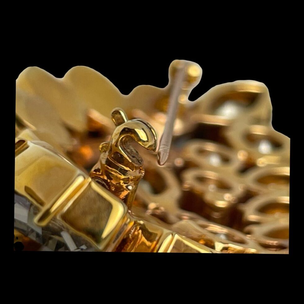 Close up photo of the pin clasp area. The clasp is shown open with the pin resting just outside.