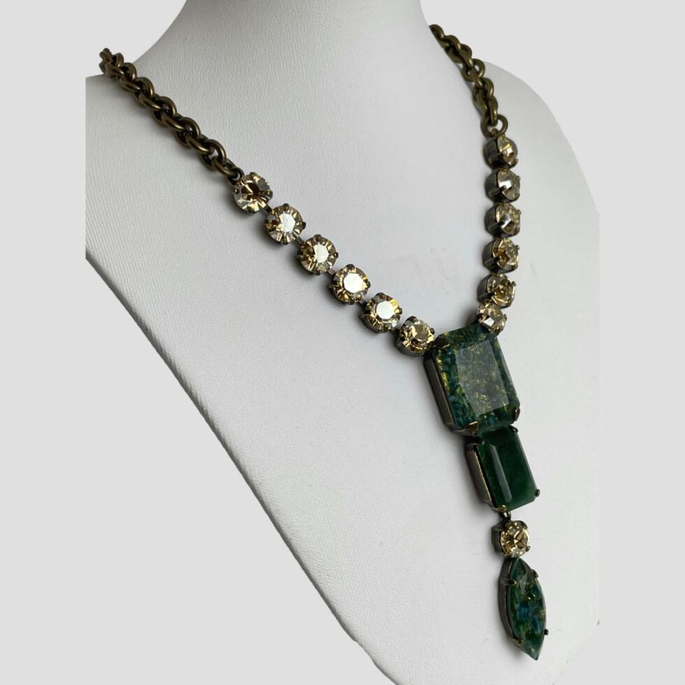 Photo of Philippe Ferrandis necklace still displayed on a white coloured stand and seen from a slight side angle with the necklace front facing to the right.