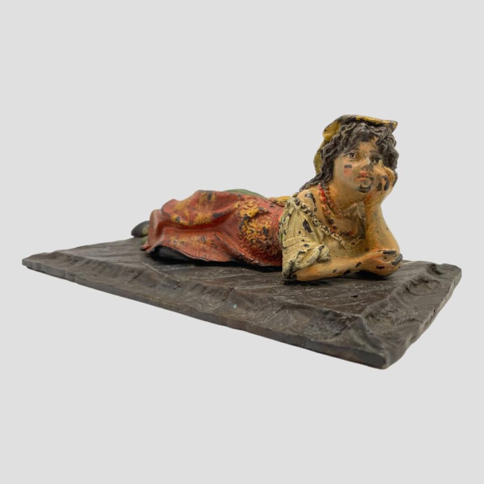 Photo of bronze Bedouin girl seen this time facing camera with the rectangular base laid diagonally across the page.