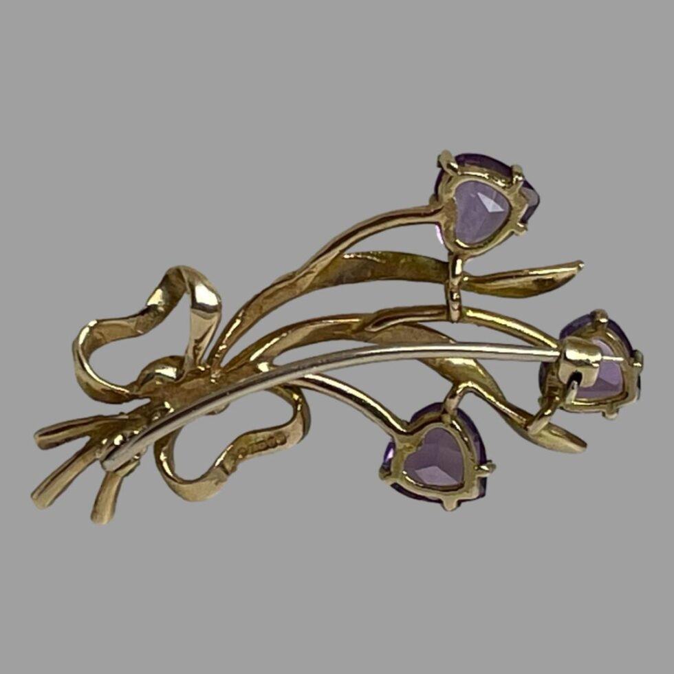 Photo of the back of the brooch with the flower head end on the right and bow on left. This photo shows the curved design of the brooch including the pin!