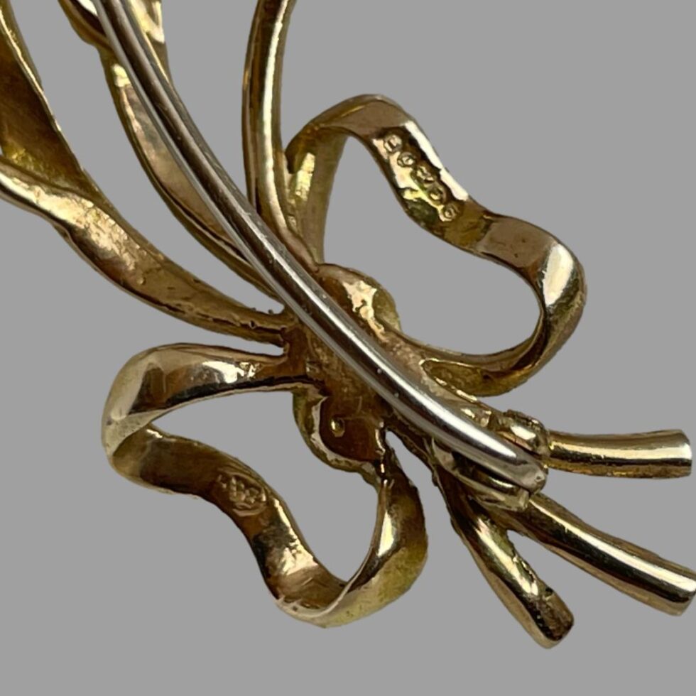 Photo of the back of the ribbon area of brooch showing the hallmark.