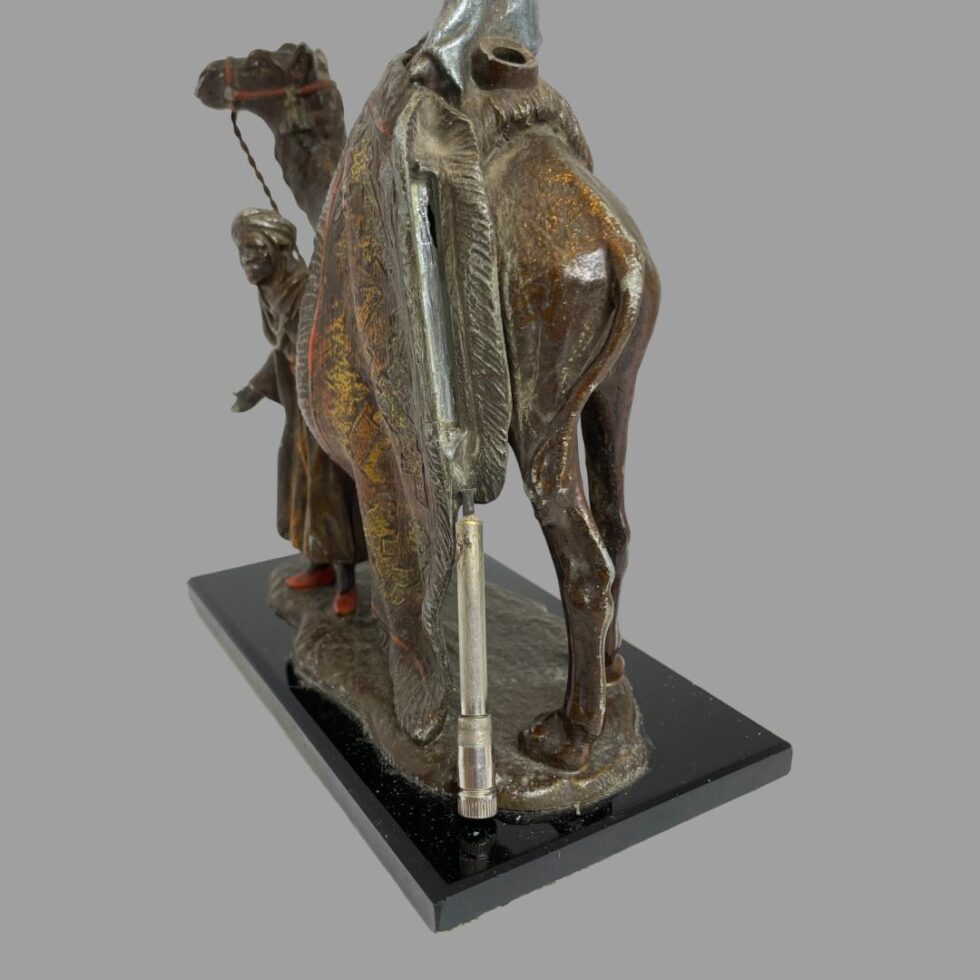 Photo of the rug merchants this time displayed from the back of the camel showing the striker which has been removed leaning against the strike section of the figurine which is between the rug and the camel.