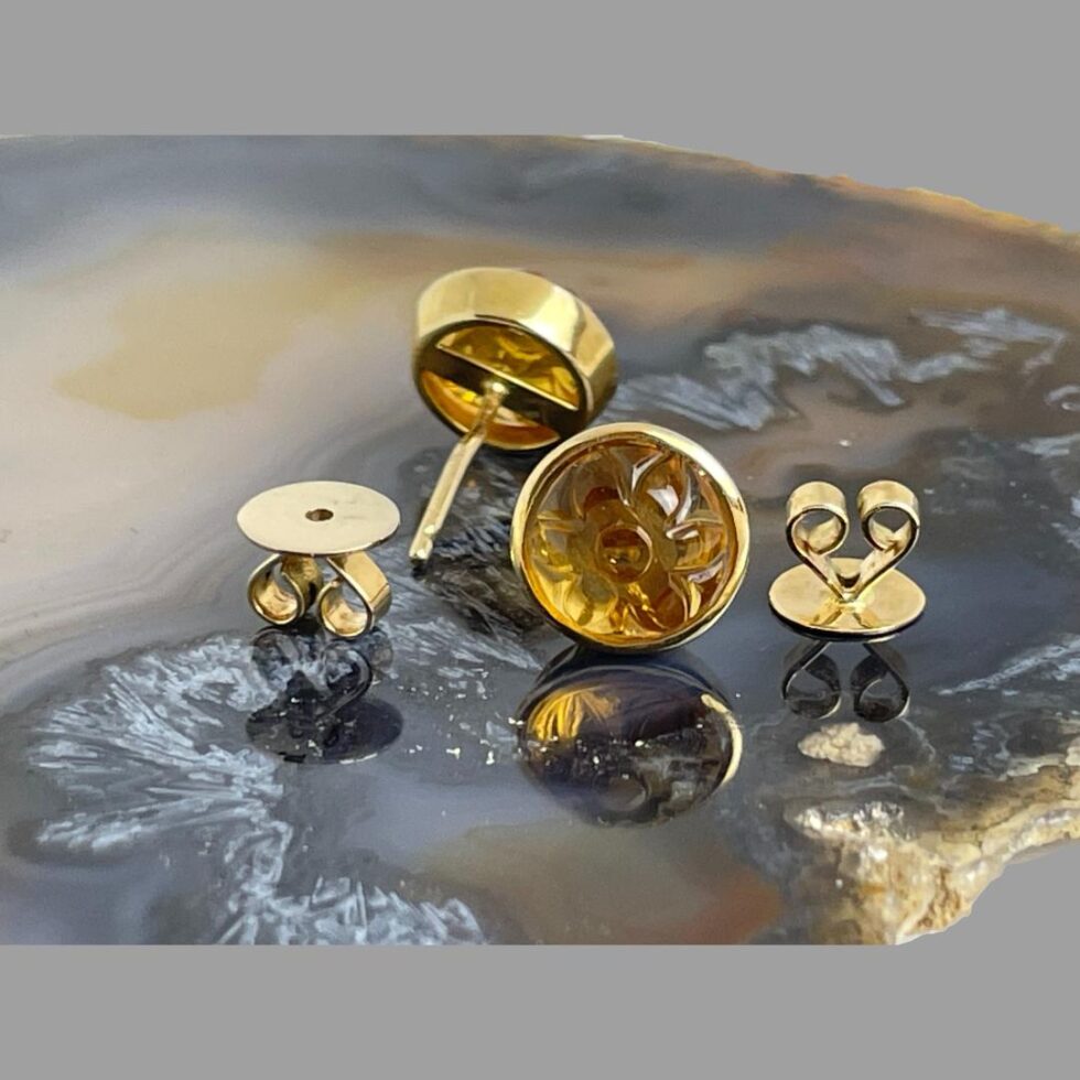 Photo of both citrine studs with left one facing away from camera showing the back and right one forward facing. Bother studs have their butterflies removed showing one face up and other flat side down.