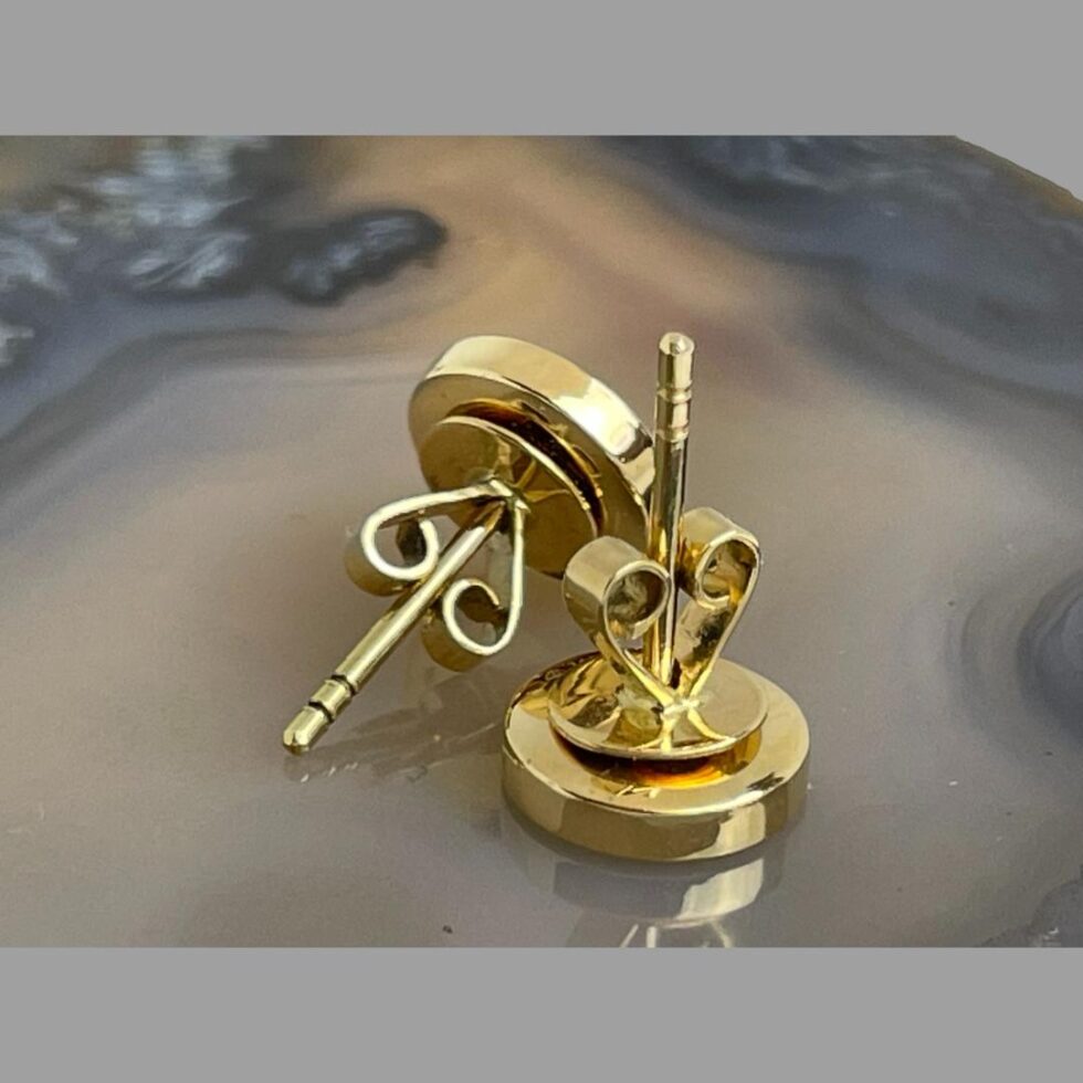 Photo of the back and post areas of the earrings. One is front face down with the post up in the air with butterfly attached and other is laid diagonally across with the post pointing to the bottom left corner. The butterflies are nice and sturdy with a wide circle back to hold earrings securely in place when worn.