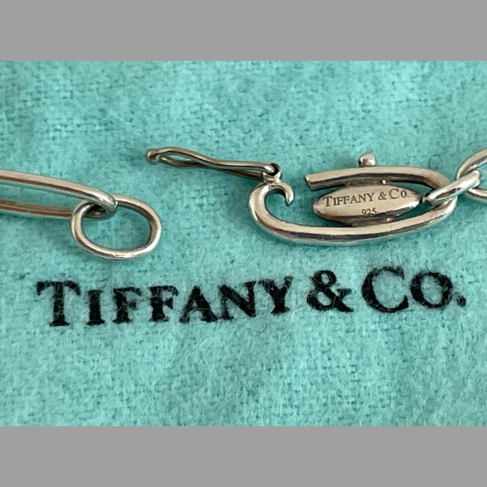 Photo of clasp area this time shown with the bracelet undone. The hinge closure is open and the ring end is lightly away to the left. The plaque this sides reads Tiffany & Co 925