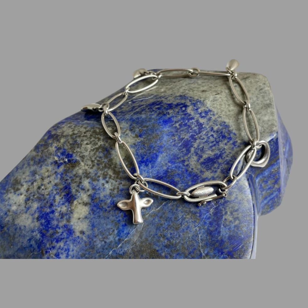 A more close up photo of Elsa Peretti charm bracelet still displayed on top of rock of natural lapis this time with the remaining 2 charms and clasp on show.