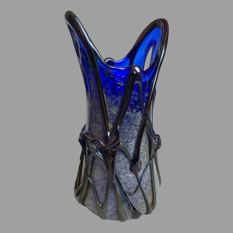 Photo of the 2 point tipped vase only seen from an eye level with lower tip on the right with hole through the glass visible and taller pointed tip to the left