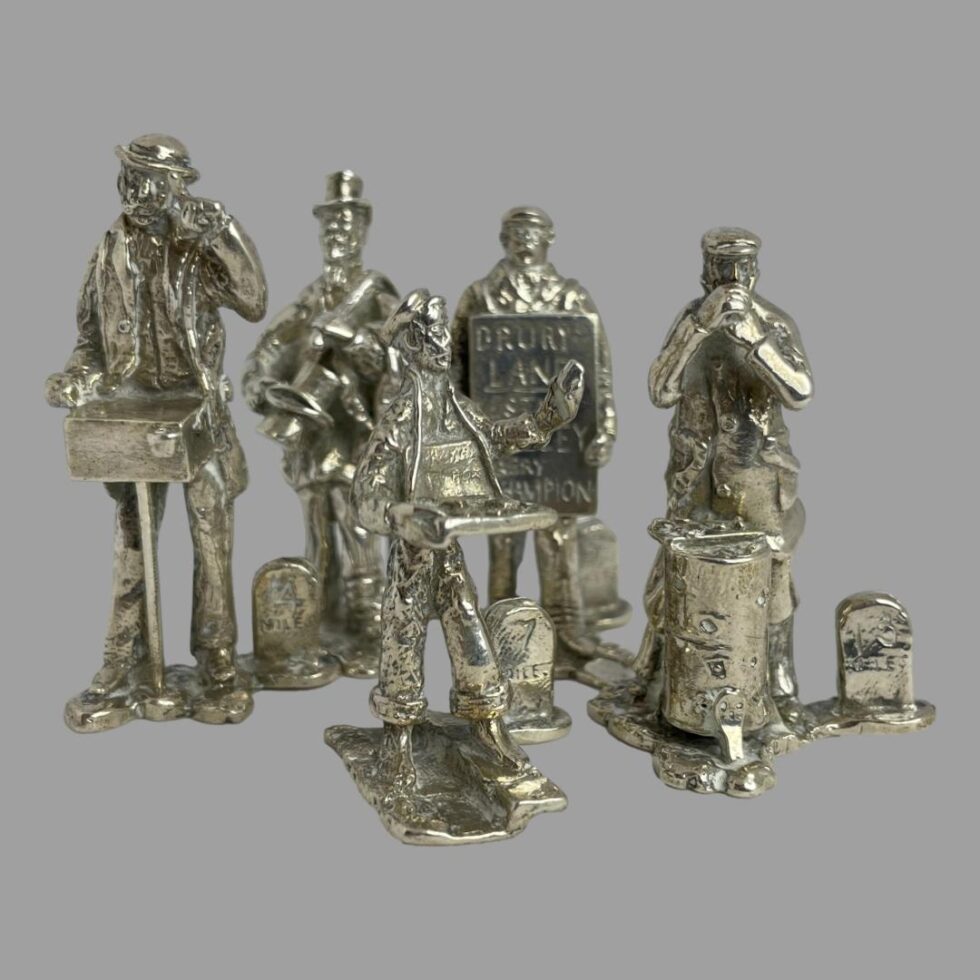 Photo of 5 of the 10 figures shown in close up. In the foreground is our match seller with his wares in a peddlers tray hung round his neck and in the background from left to right are the organ grinder (no monkey-hopefully escaped!), the top hat and clothes seller, the theatre sandwich board man and the roast chestnut seller each with their tools of the trade.
