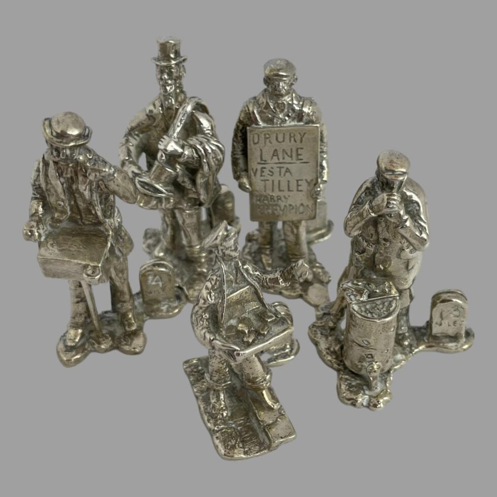 Photo of the group including roast chestnut seller seen from a slightly raised angle looking diagonally down to show their tools better.