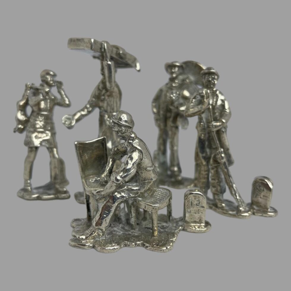 Photo of 5 of the 10 figures this group includes the cane chair repairer in the foreground with left to right the rabbit seller with rabbits hanging from a pole over his shoulder, the muffin man? with a large tray on his head, the chimney sweep with his sweep and the road sweeper with his brush.
