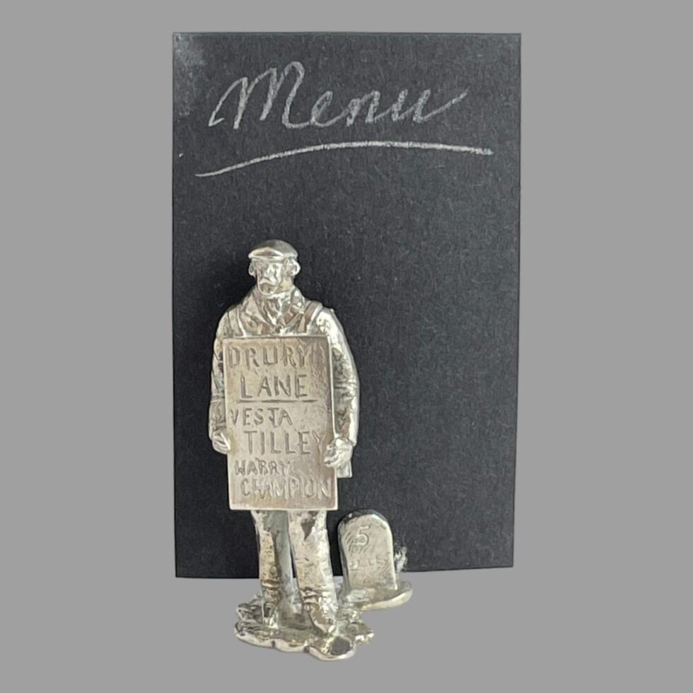 A photo of the theatre sandwich board man with a 'menu' card displayed in its slot behind him.