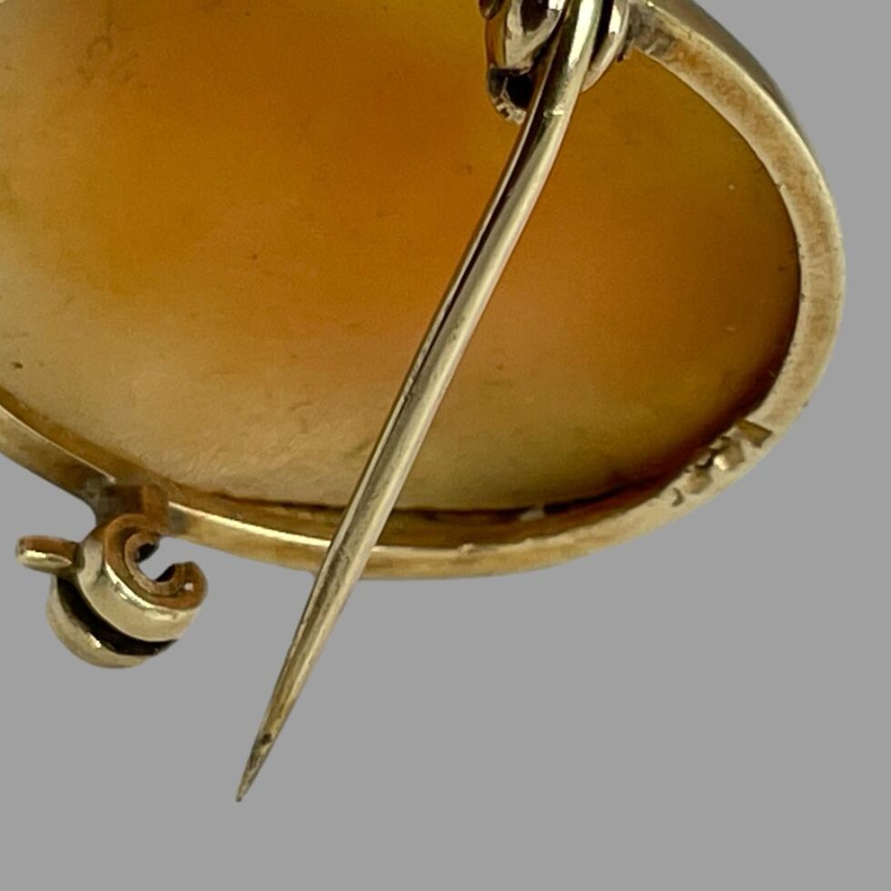 Close up photo of the illegible hallmark on the outer rim of gold frame at back of cameo.