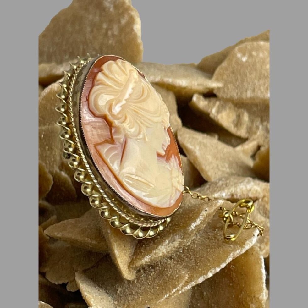Photo of 18kt gold cameo brooch still displayed on a rock of natural desert rose this time with the brooch facing towards the right giving an idea of the depth of the brooch.
