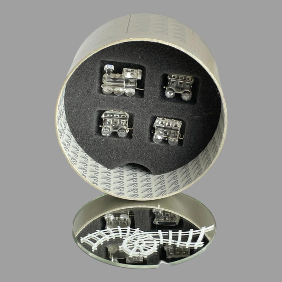 Photo of Swarovski train set with each piece in its fitted foam slot inside the box. The round mirror with the white track is in the foreground outside of the box. The mirror track will fit in to box with padding.