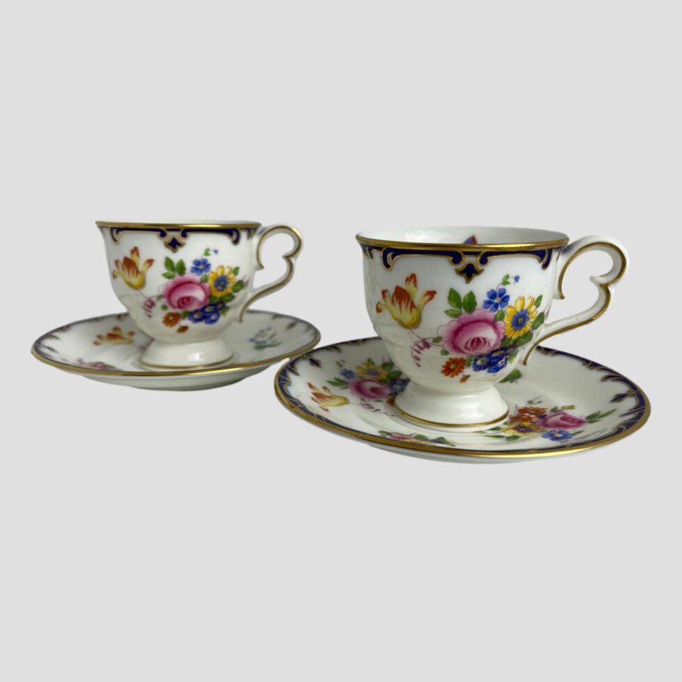 Main photo of pair Cauldon cups &saucers displayed side by side with cups on their saucers. The cups are small so ideally suit espresso coffees or specialist teas. Each cup and saucer is beautifully decorated with vibrant flowers in different bright colours with a lovely butterfly on the saucer dip and inside of cup.