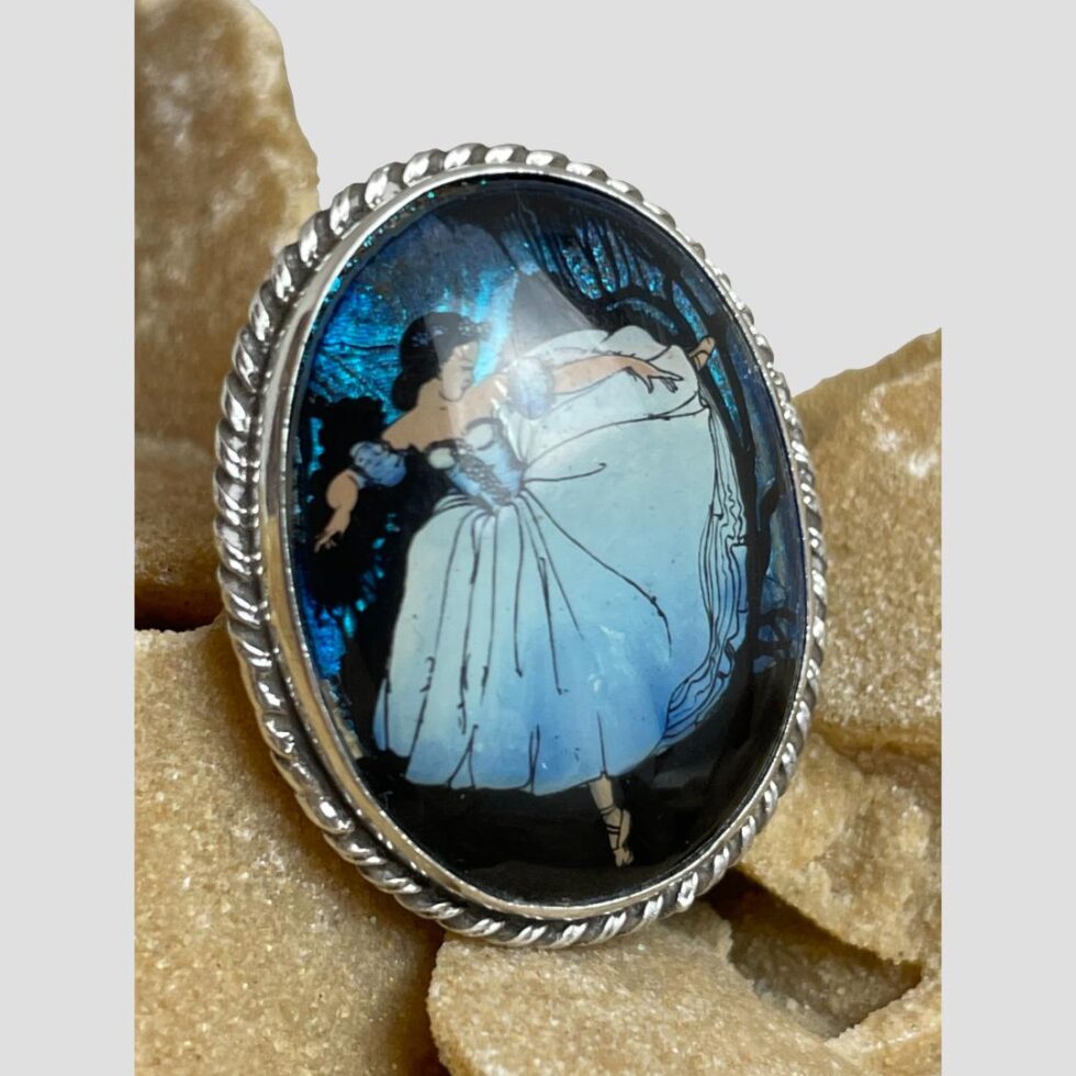 Photo of ballerina butterfly wing brooch displayed this time with the brooch front facing to the bottom right corner. The light is reflecting on the outer casing and the blue butterfly wings are looking more electric.