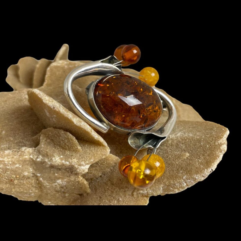 Photo of silver amber brooch seen from more of a side angle this time with the stamen balls in the centre top and bottom.